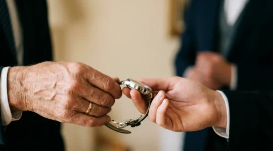 Passaggio di un orologio di lusso tra mani di diverse generazioni durante cerimonia importante