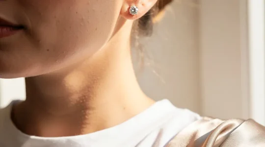 Orecchini punto luce di diamanti indossati da donna elegante su sfondo neutro