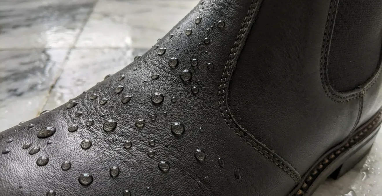 Dettaglio stivaletti Chelsea in pelle trattata su pavimento bagnato